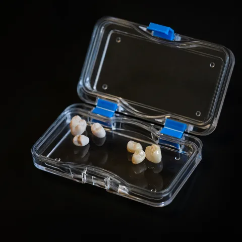 Dental crowns in an open transparent protective case.